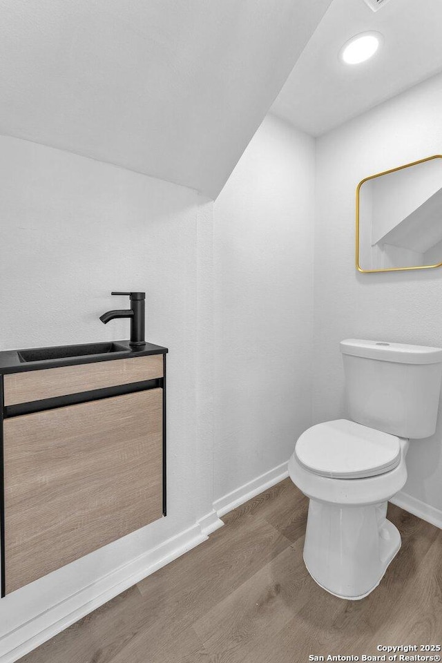 bathroom with hardwood / wood-style flooring, vanity, and toilet