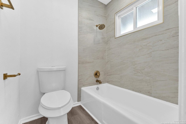 bathroom featuring hardwood / wood-style floors, tiled shower / bath combo, and toilet