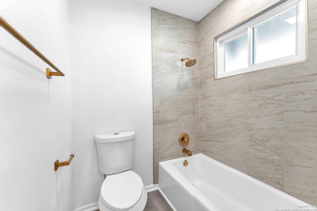 bathroom with tiled shower / bath combo and toilet