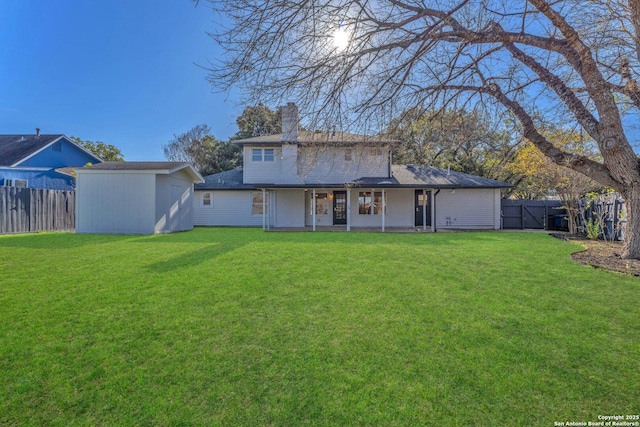 rear view of property featuring a yard and an outdoor structure