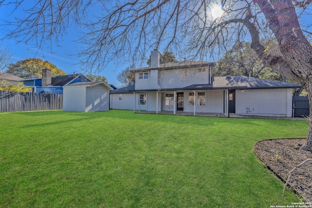 back of house with a lawn, a storage unit, and a patio area