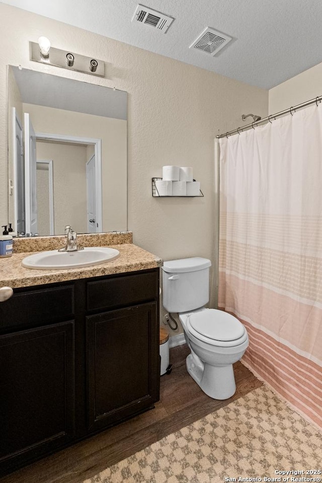 bathroom featuring a textured ceiling, toilet, wood-type flooring, and vanity