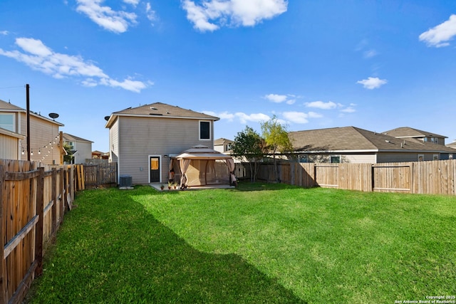 back of property with central AC unit, a gazebo, and a yard