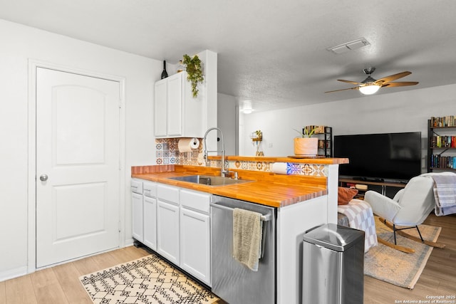 kitchen featuring white cabinetry, ceiling fan, a textured ceiling, stainless steel dishwasher, and sink