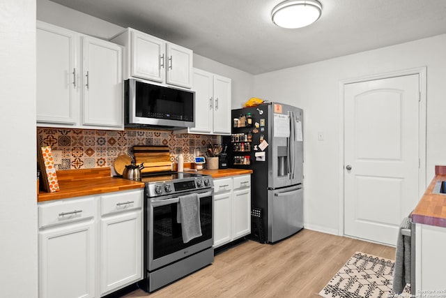 kitchen with wood counters, white cabinetry, light hardwood / wood-style floors, stainless steel appliances, and tasteful backsplash