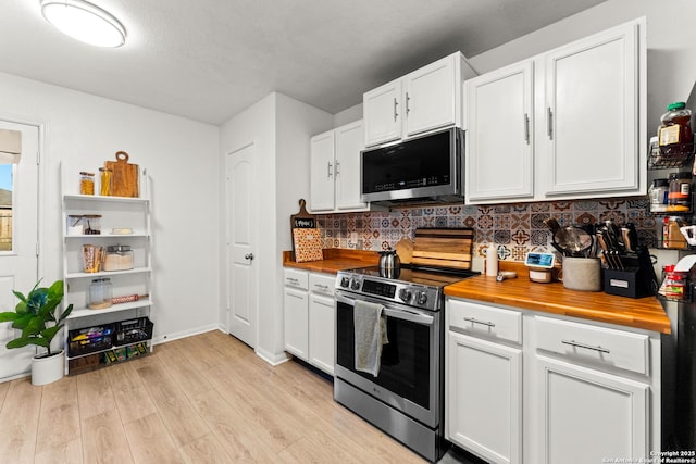 kitchen featuring white cabinetry, light hardwood / wood-style floors, wooden counters, appliances with stainless steel finishes, and decorative backsplash