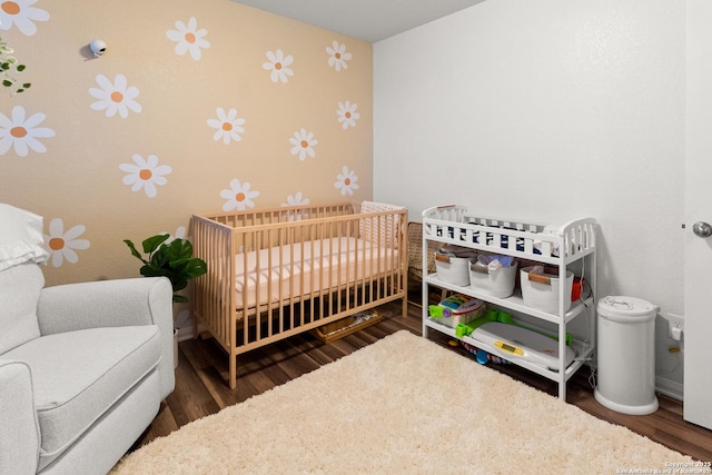 bedroom featuring dark wood-type flooring and a crib