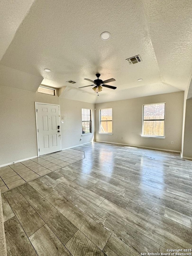 empty room featuring a textured ceiling, ceiling fan, and lofted ceiling