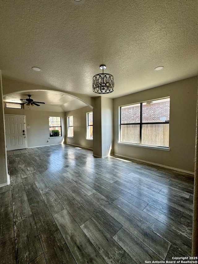 unfurnished living room featuring a textured ceiling, dark hardwood / wood-style floors, and ceiling fan with notable chandelier