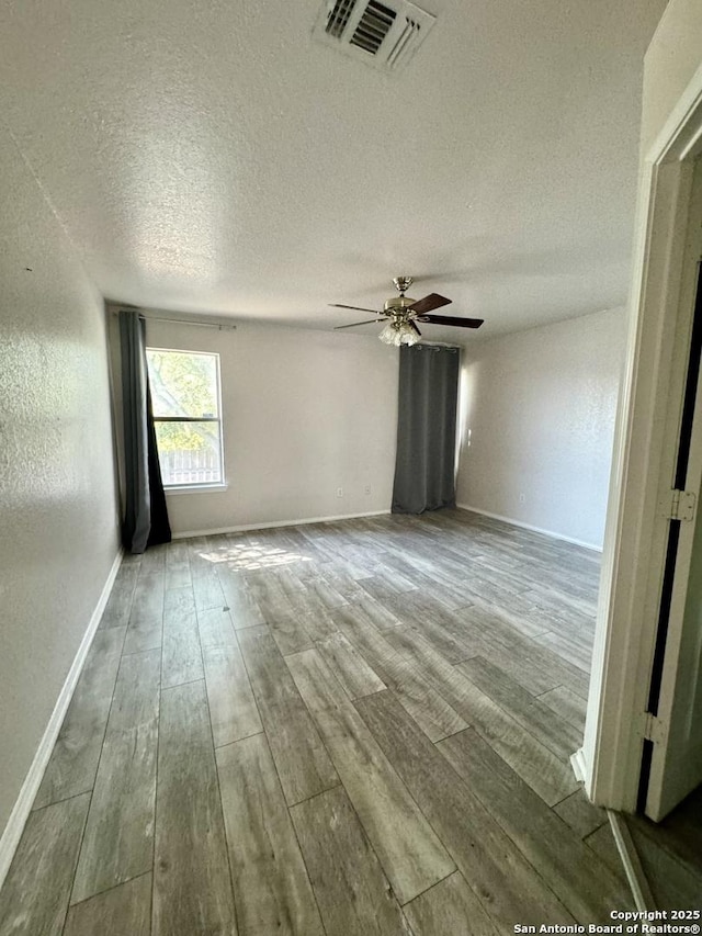 empty room with wood-type flooring, a textured ceiling, and ceiling fan