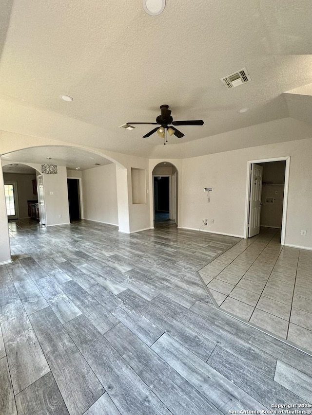 unfurnished living room with a textured ceiling and ceiling fan