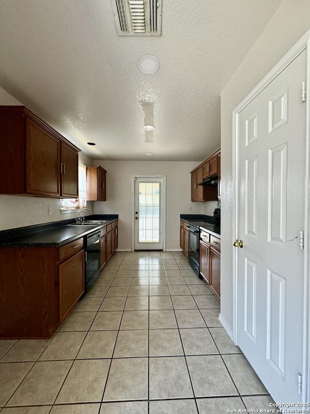 kitchen featuring light tile patterned flooring, a textured ceiling, sink, and black appliances