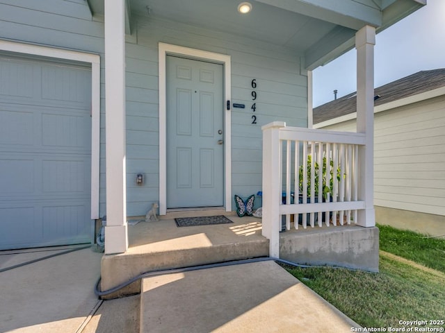 view of exterior entry with a porch and a garage