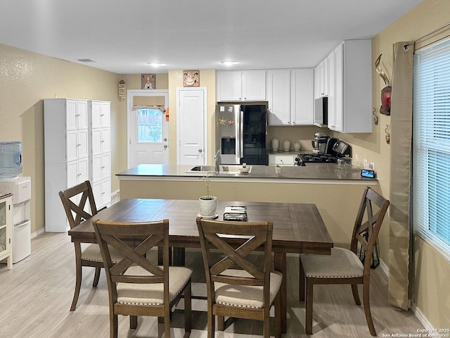 kitchen featuring kitchen peninsula, stainless steel appliances, white cabinetry, and sink