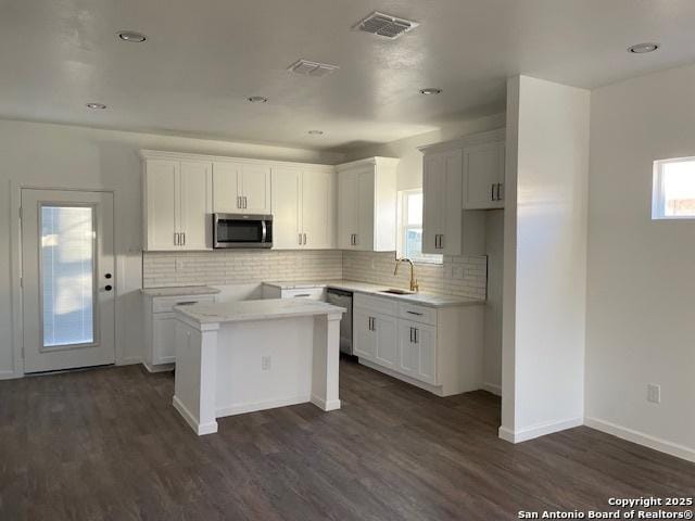 kitchen featuring white cabinets, dark hardwood / wood-style floors, a center island, and appliances with stainless steel finishes