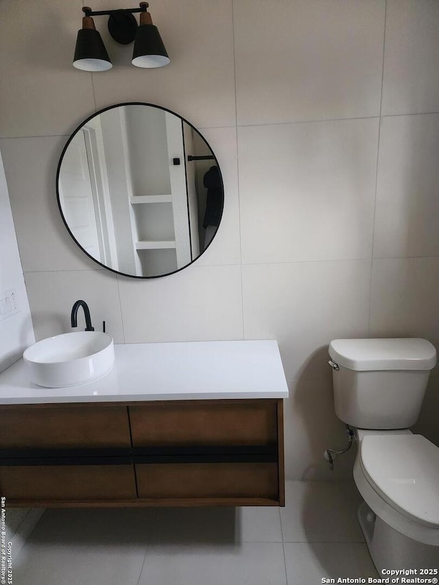 bathroom with tile patterned flooring, vanity, toilet, and tile walls