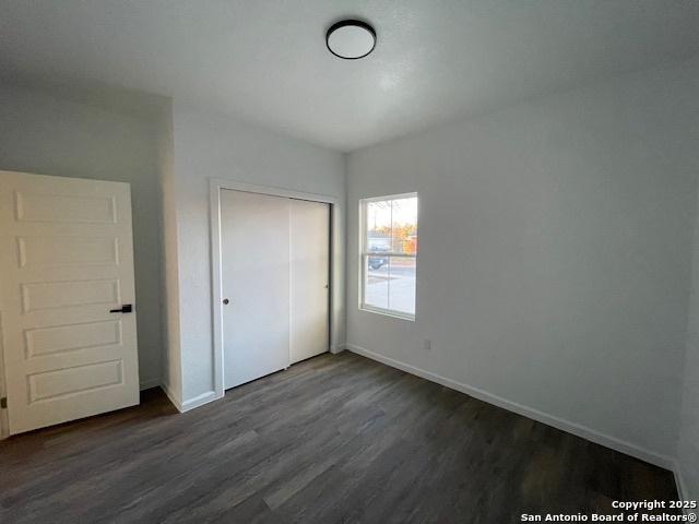 unfurnished bedroom featuring dark hardwood / wood-style flooring and a closet