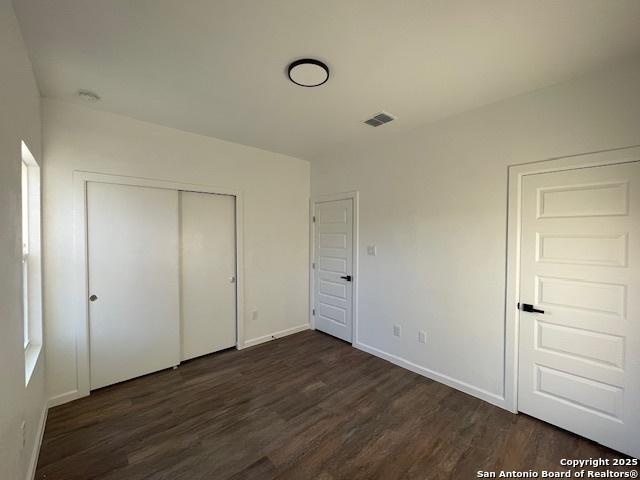 unfurnished bedroom featuring a closet and dark wood-type flooring