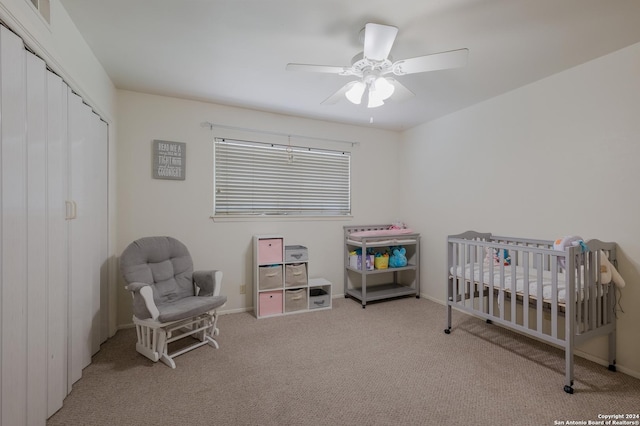 bedroom with ceiling fan, a closet, a nursery area, and light carpet