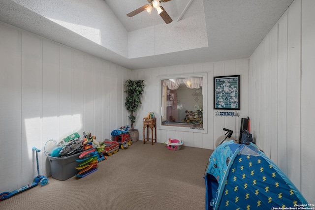 carpeted bedroom featuring vaulted ceiling, ceiling fan, a tray ceiling, and a textured ceiling