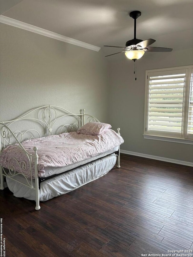 bedroom featuring dark wood-type flooring, ceiling fan, and ornamental molding