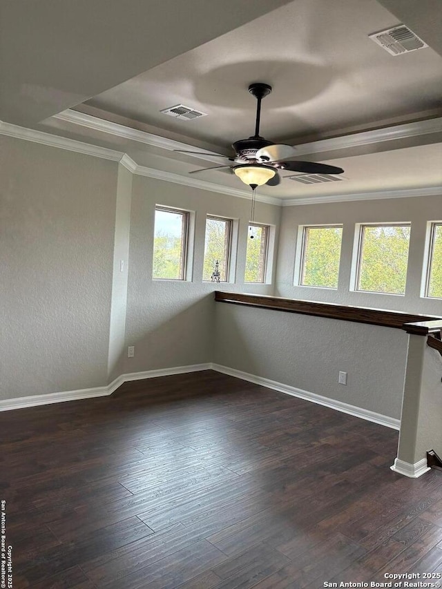 spare room with a tray ceiling, ceiling fan, dark hardwood / wood-style flooring, and ornamental molding