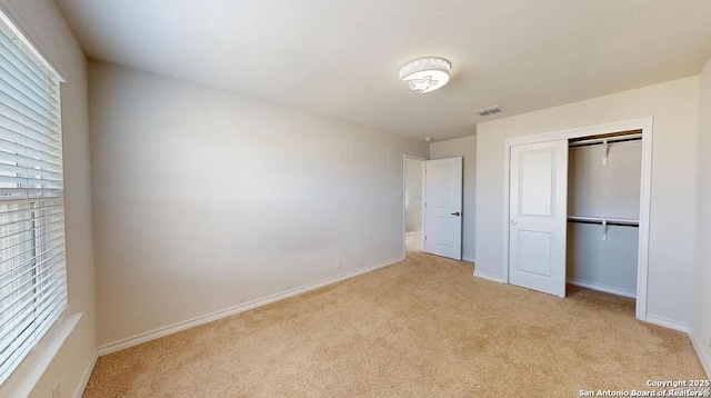 unfurnished bedroom with light carpet and a closet