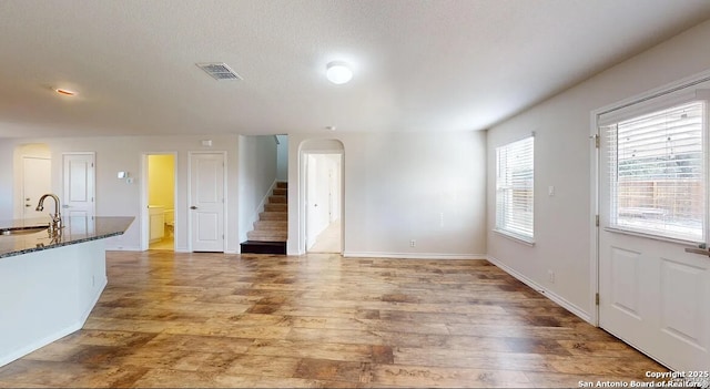 unfurnished living room with sink, wood-type flooring, and a textured ceiling