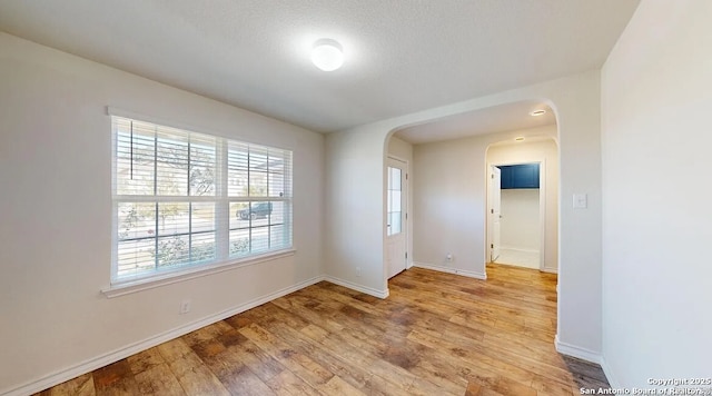 unfurnished room with hardwood / wood-style floors and a textured ceiling