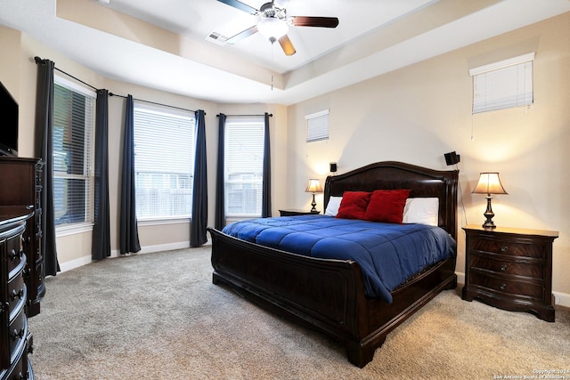 carpeted bedroom featuring a tray ceiling and ceiling fan