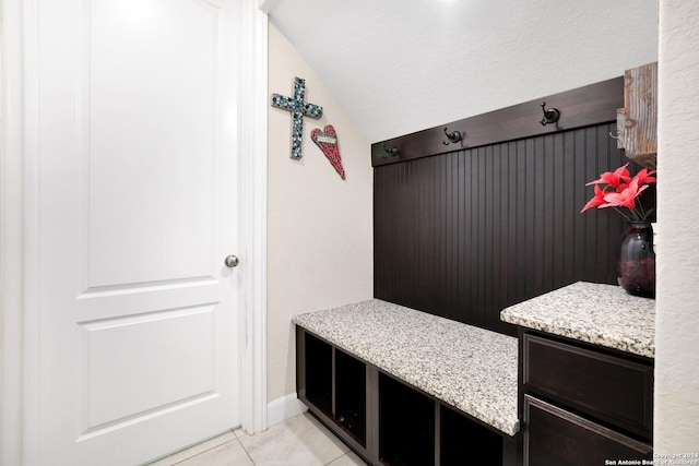 mudroom with light tile patterned floors and vaulted ceiling