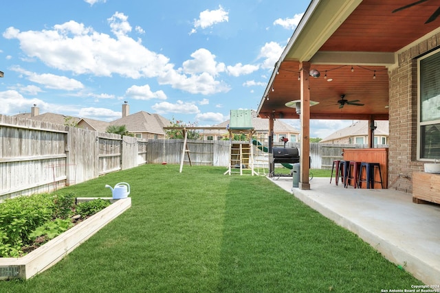 view of yard with a bar, a playground, ceiling fan, and a patio area