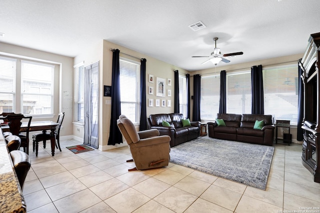 living room featuring ceiling fan, light tile patterned flooring, and a textured ceiling