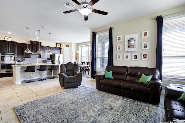 living room featuring a wealth of natural light, sink, ceiling fan, and light tile patterned flooring