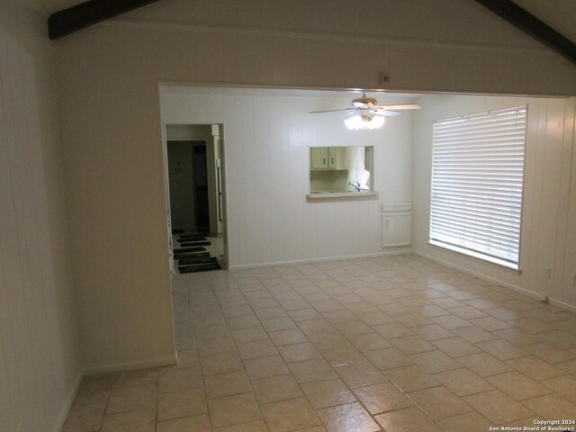 tiled empty room featuring beam ceiling and ceiling fan