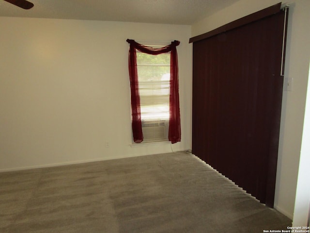 spare room featuring cooling unit, ceiling fan, and carpet