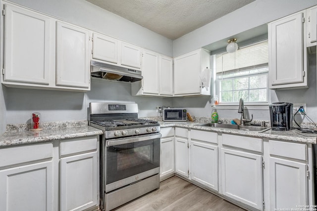 kitchen featuring white cabinets, sink, gas range, light wood-type flooring, and a textured ceiling