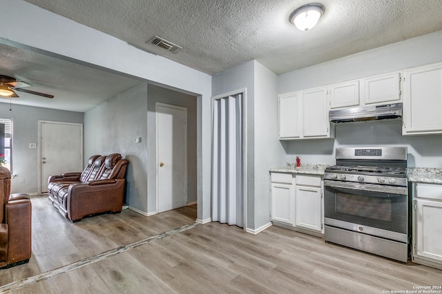 kitchen featuring white cabinets, a textured ceiling, stainless steel gas stove, and light hardwood / wood-style flooring