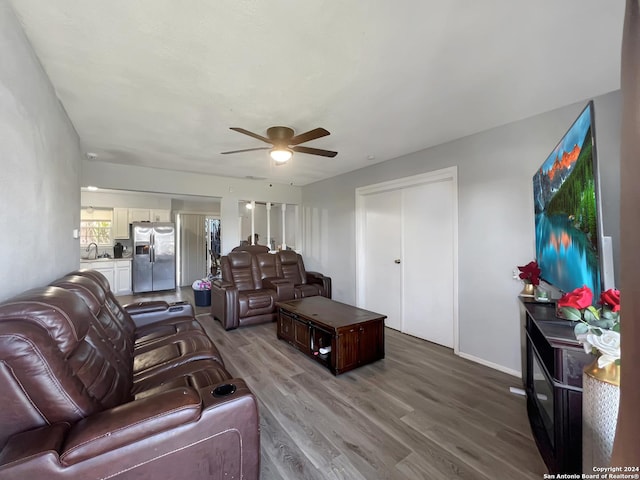 living room featuring light wood-type flooring, ceiling fan, and sink