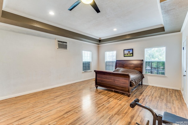 bedroom featuring a tray ceiling, crown molding, light hardwood / wood-style flooring, and ceiling fan