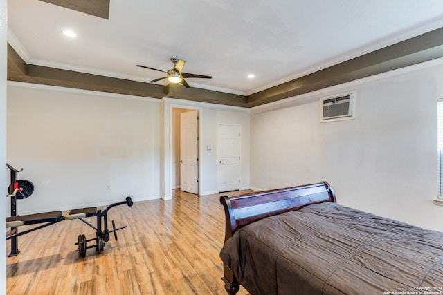 bedroom with light wood-type flooring, a raised ceiling, a wall mounted AC, crown molding, and ceiling fan