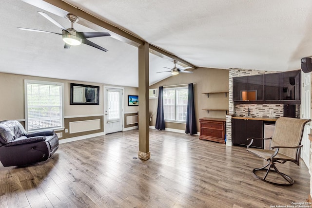 living room with a textured ceiling, vaulted ceiling with beams, and hardwood / wood-style flooring