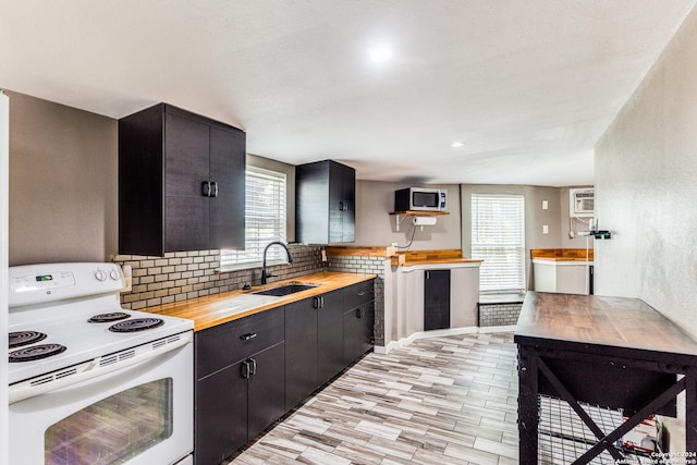 kitchen with white range with electric stovetop, plenty of natural light, sink, and wooden counters