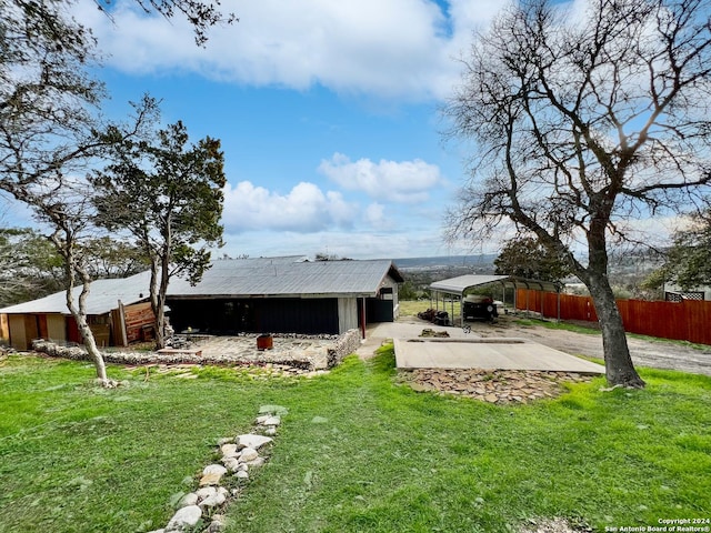 back of property with a lawn, a carport, and an outdoor structure