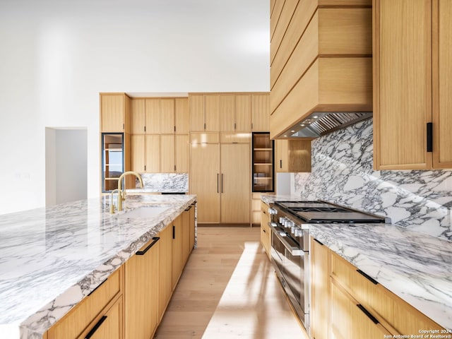 kitchen featuring high end stove, light brown cabinetry, and premium range hood