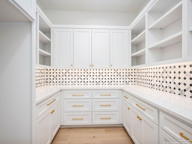 kitchen with white cabinetry, light hardwood / wood-style flooring, and tasteful backsplash