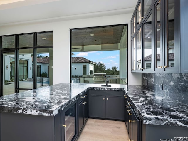 kitchen with tasteful backsplash, kitchen peninsula, beverage cooler, and dark stone counters