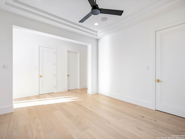 interior space with ceiling fan, light wood-type flooring, and a tray ceiling