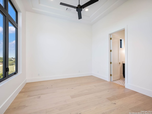 spare room with light hardwood / wood-style flooring, a raised ceiling, and ceiling fan