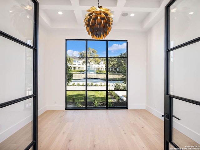 spare room with beam ceiling, light hardwood / wood-style flooring, plenty of natural light, and coffered ceiling